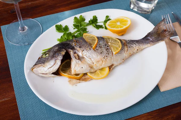 Top view of whole grilled dorada served with lemon and greens at plate — Stock Photo, Image