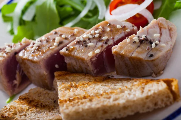 Closeup of seared tuna steaks with greens and grilled bread — Stock Photo, Image