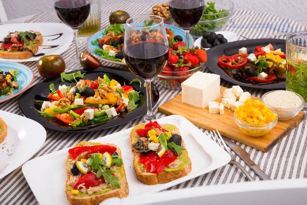 Many plates with tasty vegetarian food and wine in glass — Stock Photo, Image