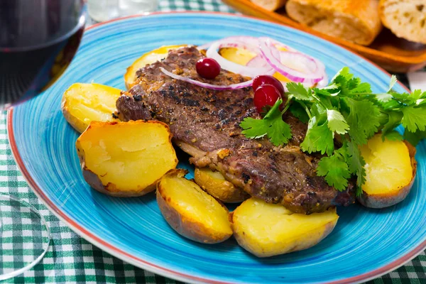 Beef steak with baked potatoes served at plate with greens — Stock Photo, Image