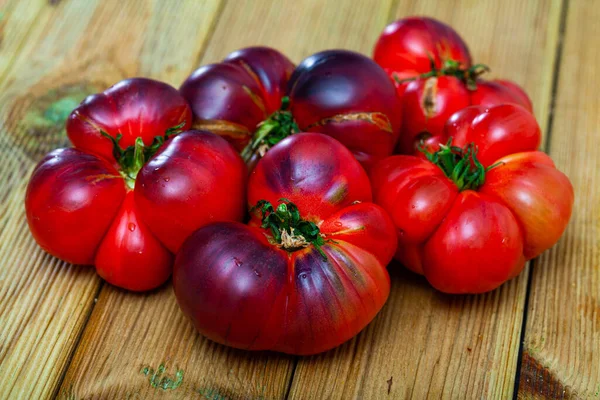 Tomates azules y cuchillo en tabla de cortar de madera — Foto de Stock