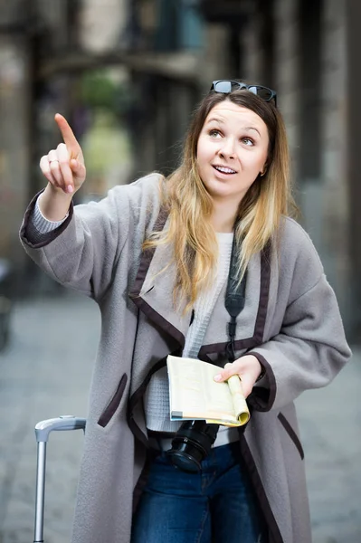 Traveling girl searching for the direction using a booklet in the town — Stock Photo, Image