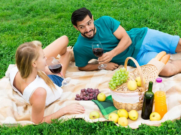 Glimlachend koppel ligt met wijnglazen en praten — Stockfoto