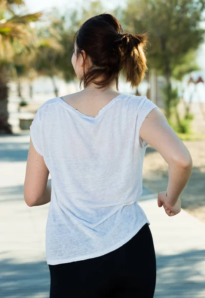 Kvinna 20-30 år gammal joggar tillbaka i svart t-shirt — Stockfoto