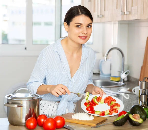 Frau probiert Gemüsesalat in Küche — Stockfoto