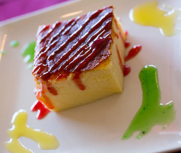 Zoete dessert kaastaart geserveerd met kleurrijke room op bord — Stockfoto