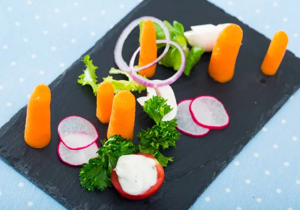 Vegetariánská mísa, mrkev se zeleninou, cibule a rajčata podávané na černém talíři — Stock fotografie