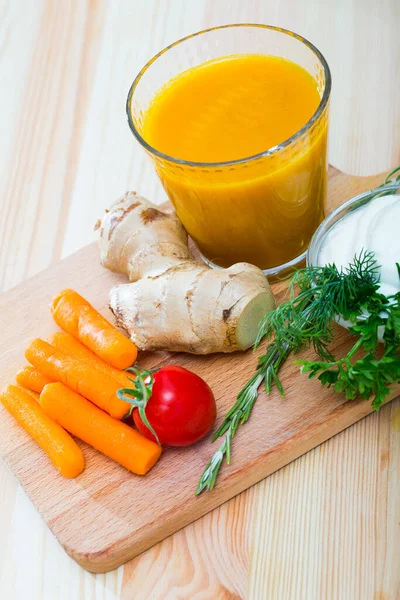 Vidro com suco de cenoura com gengibre, verduras e legumes na mesa de madeira — Fotografia de Stock
