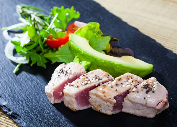 Sabroso pescado de atún crudo, aguacate fresco y verduras servidas en el plato —  Fotos de Stock