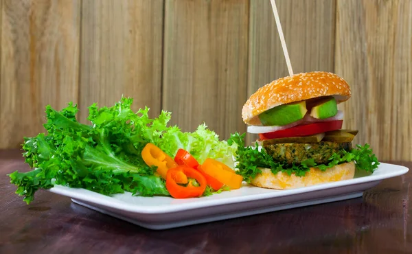 Hambúrguer vegetariano com pato de soja, legumes frescos e abacate no prato — Fotografia de Stock