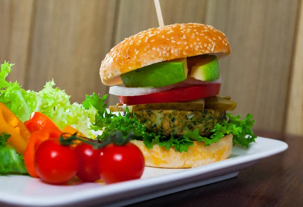 Wegetariański hamburger z pasztetem sojowym, świeże warzywa i awokado na talerzu — Zdjęcie stockowe