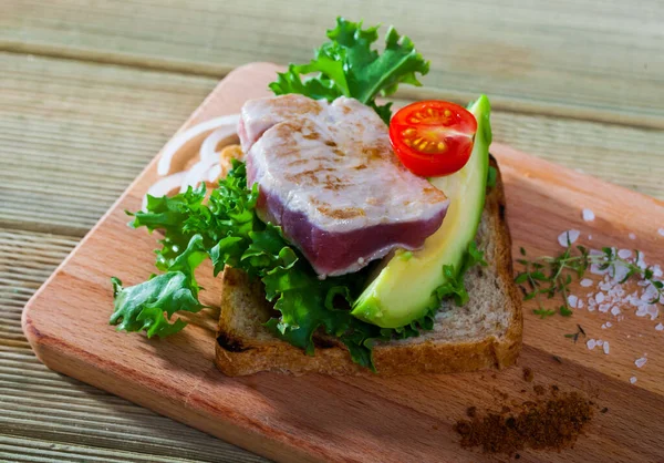 Delicious pieces raw tuna, green avocado and greens at plate — Stock Photo, Image