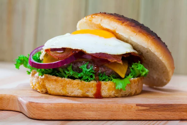 Гамбургер с яичницей, беконом, сыром, салатом, луком — стоковое фото