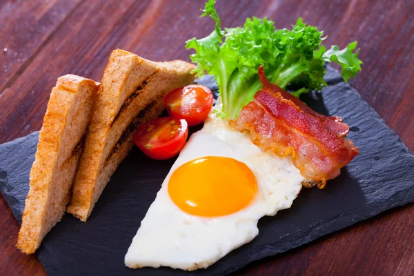 Gebratene Eier mit Speck, Toastbrot und Tomaten auf dem Teller, amerikanisches Frühstück — Stockfoto
