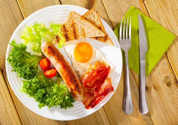 Sabroso desayuno de salchichas, tocino, huevos revueltos —  Fotos de Stock
