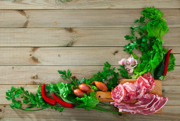 Fresh slices of lamb and vegetables assortment on natural wooden desk — Stock Photo, Image