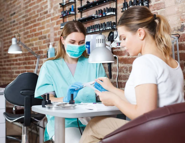 Professionelle Maniküre in Maske macht Maniküre von Nagel zu Mädchen — Stockfoto