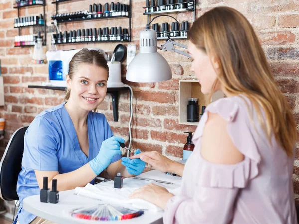 Manicurista che fa la procedura di manicure unghie a cliente di donna in salone — Foto Stock