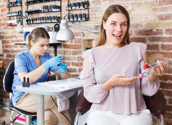 Girl client demonstration polish color schemes in nail salon — Stock Photo, Image