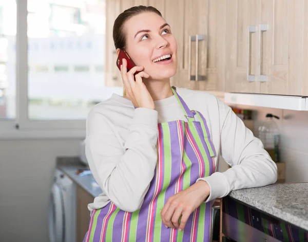 Jeune femme parle par téléphone avec une petite amie dans la cuisine — Photo