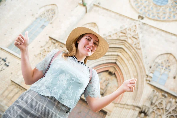 Joven mujer emocional en sombrero sosteniendo pulgares en el centro de la ciudad — Foto de Stock