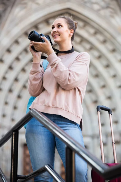 Young woman holding camera in hands and photographing in city — Stock Photo, Image