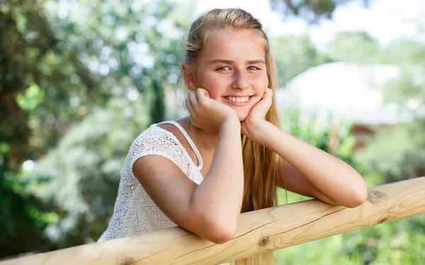 Teenage cute girl standing near fence in green park at sunny day — ストック写真