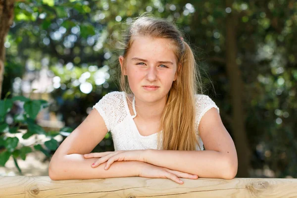 Portrait of tired teen girl standing near fence in summer green park — Stock Photo, Image
