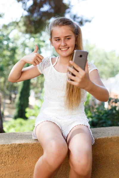 Vrolijke tiener meisje maken selfie met telefoon in de zomer groen park — Stockfoto