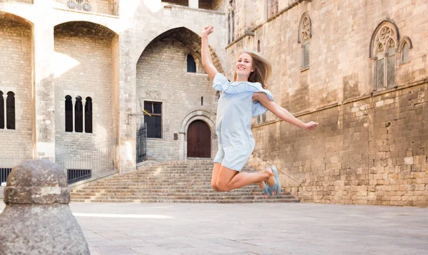 Girl jumping up against stone building — Stock Photo, Image