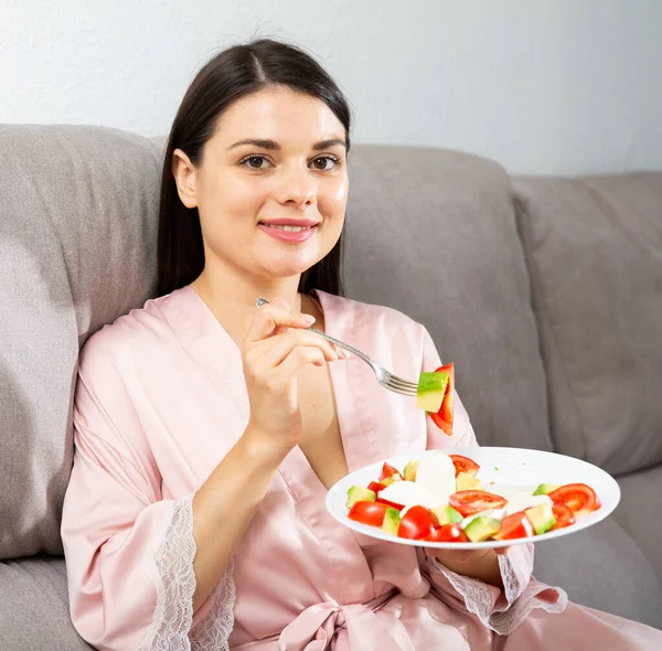 Woman eating salad on sofa — Stock Photo, Image