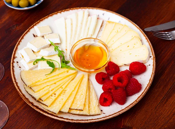 Diversi tipi di formaggio affettato e servito su piatto — Foto Stock