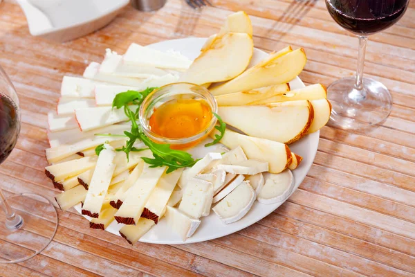 Various types of cheese and pear slices on plate — Stock Photo, Image