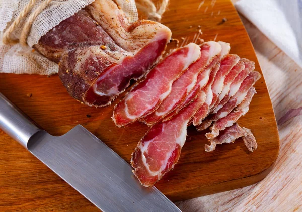 Нарезанная вяленая свиная вырезка со специями на деревянном фоне — стоковое фото
