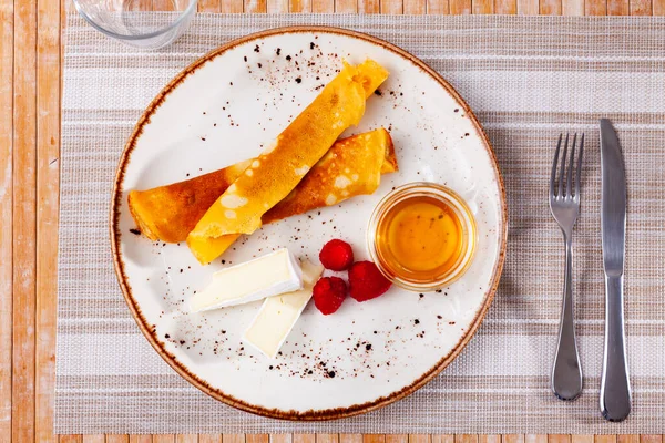 Crepes sottili con fette di brie morbido, miele e lamponi — Foto Stock