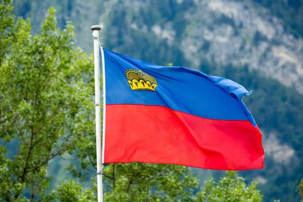 Bandera de Liechtenstein ondeando sobre fondo de montaña — Foto de Stock