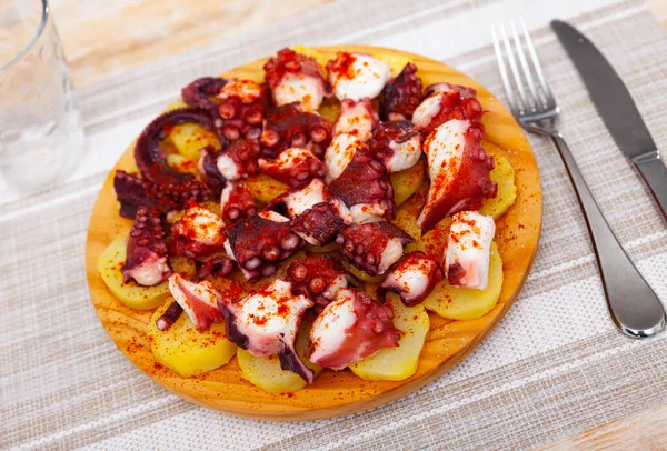 Galician boiled octopus with smoked paprika and potatoes on wooden board — Stock Photo, Image