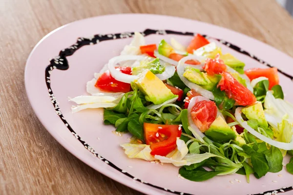 Салат з авокадо, помідорами, грейпфрутом та кукурудзяним салатом на тарілці — стокове фото
