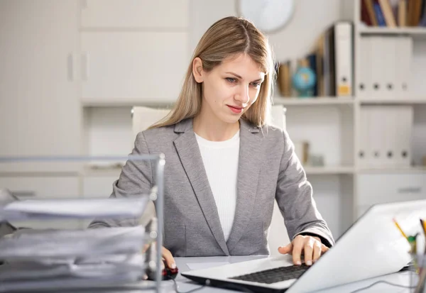Жінка букмекер сидить за столом і використовує ноутбук — стокове фото