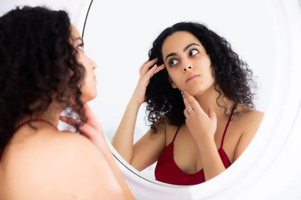 Vrouw kijkt haar gezicht in de spiegel in de ochtend — Stockfoto