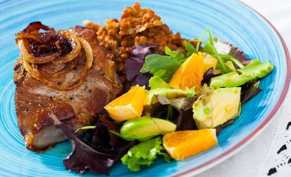 Leckeres gebratenes Schweinefleisch mit Linsen, Avocado und Orange auf dem Teller — Stockfoto