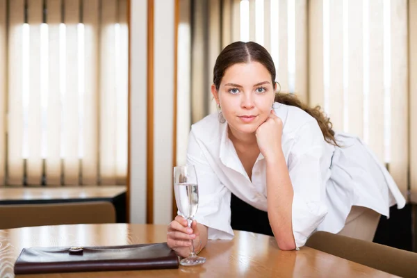 Vrolijke jonge vrouw met glas champagne poseren op kantoor — Stockfoto