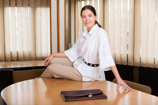 Attraktiv kvinna med portfölj sittande på bord i mötesrum — Stockfoto