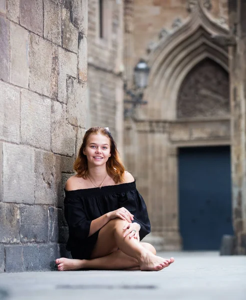 Positives Mädchen sitzt barfuß an der Steinmauer — Stockfoto