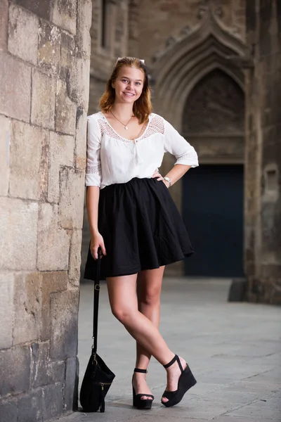 Positive young girl standing near the stone wall — Stock Photo, Image