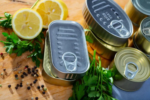 Tin cans with ring pull on wooden surface with lemon and greens — Stock Photo, Image