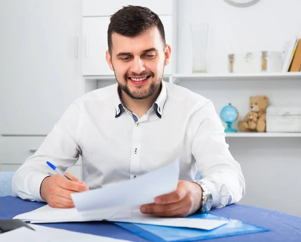 Un jeune homme souriant signe un accord financier rentable — Photo