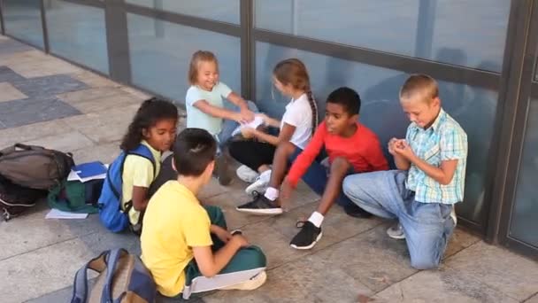 Bekymmersfri tweenagers studenter vänliga prata och ha kul nära skolan byggnad i varm höstdag — Stockvideo