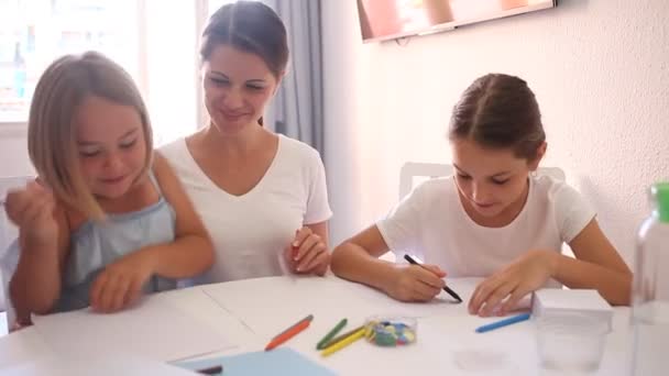 Feliz madre enseña a sus hijas a dibujar en casa — Vídeo de stock