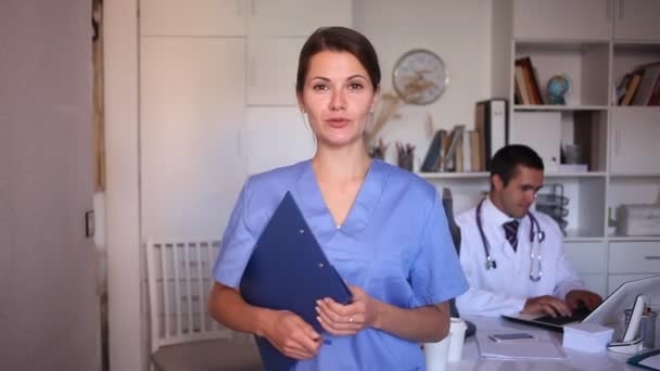 Bayan doktor hoş geldin jesti yapıyor, hastayı nazikçe muayenehaneye davet ediyor. — Stok video